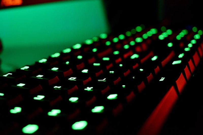 Close-up of a backlit gaming keyboard with vibrant green LED lights creating a glowing effect.