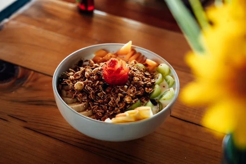Green smoothie bowl with cold brew coffee in a plant-filled cafe