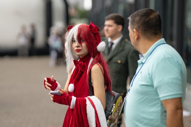 Een groep jonge anime fans zit enthousiast op een bank te kijken naar een groot scherm, lachend en wijzend naar de actie.
