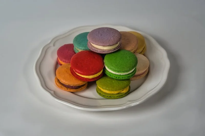 Diverse kleurrijke Franse macarons met perfecte voetjes op een witte schaal